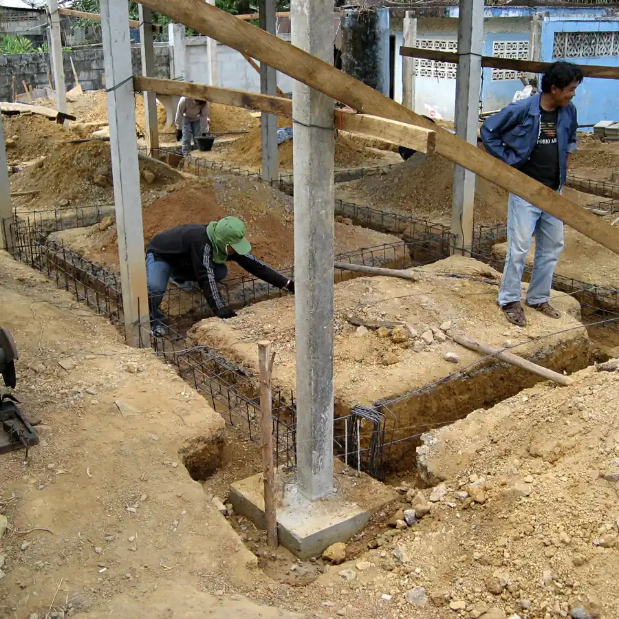 Pekerjaan perakitan pembesian tulangan sloof dan tapak pondasi pada galian tanah proyek rumah dengan tiang kolom struktur dan bekisting penguat